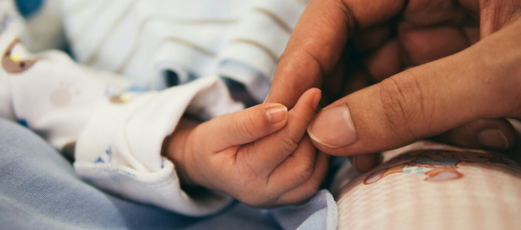 Newborn baby holding their mother's finger, close-up of hands during postpartum bonding