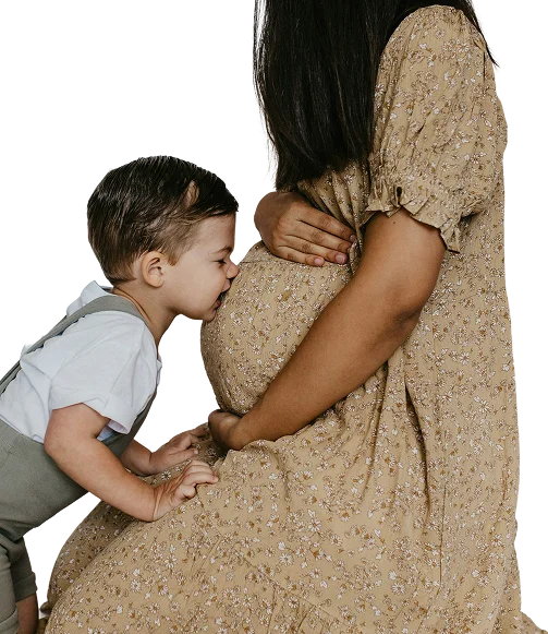 Little boy gently kissing his pregnant mother's belly, representing family bonding and healthy prenatal nutrition support